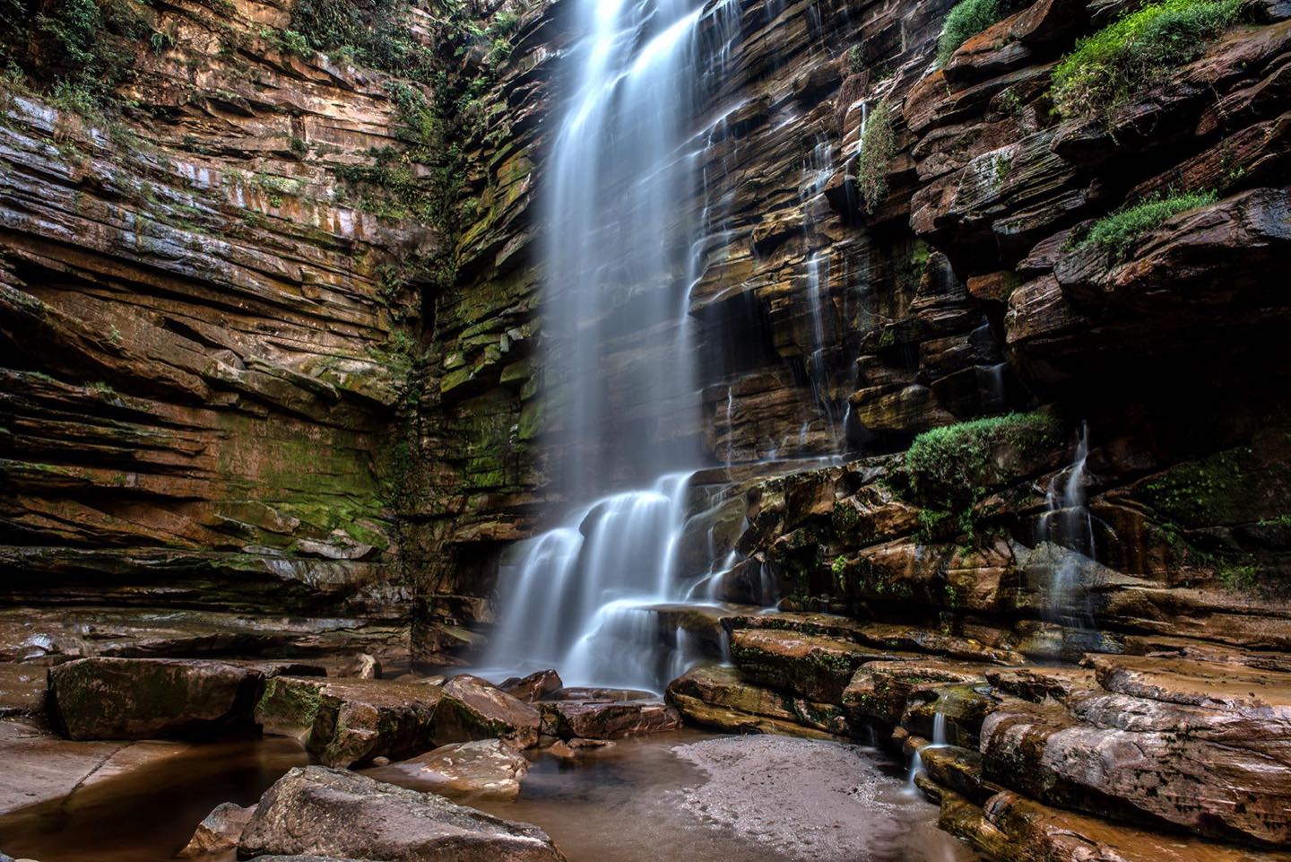 A Cachoeira do Mosquito descendo por paredes de pedra em camadas até um poço de água escura
